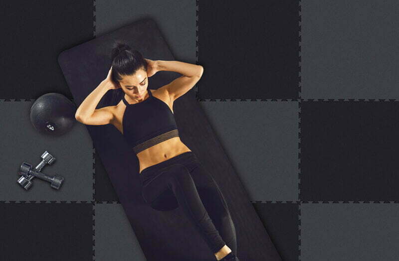 Exercises abs. Sporty girl in black sportswear doing abc exercises indoors. StudioLine Classico sportpadló
